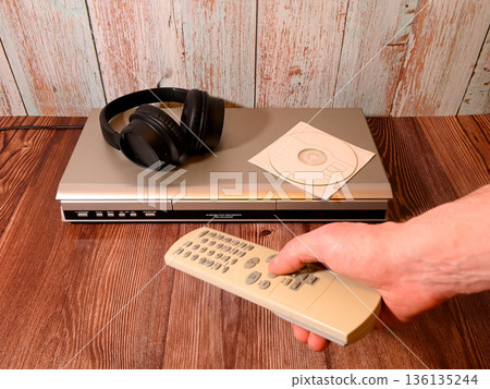 hand with a remote control aimed at a player with headphones 136135244