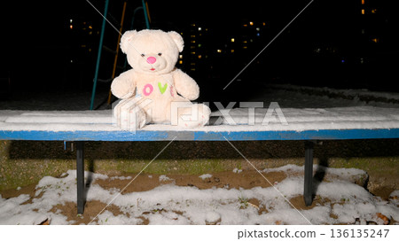 teddy bear on a snowy bench at night 136135247