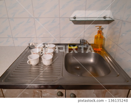 white cups on a metal sink in the kitchen 136135248