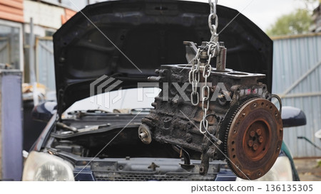 Car engine block hanging from chain for repair 136135305