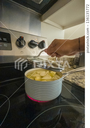 A person is cooking food in a pot on a stove 136135772