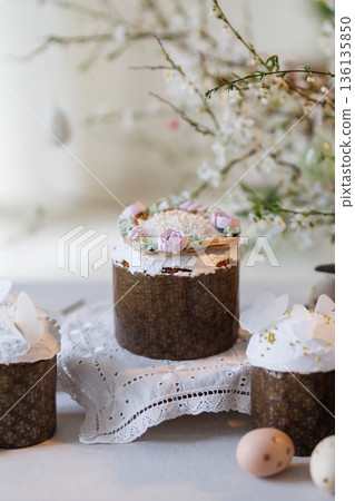 Easter cakes and eggs on lace table with spring blossom branches, soft daylight Easter cakes and eggs on lace table with spring blossom branches, soft daylight 136135850