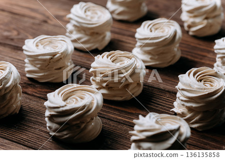 Vanilla meringue swirls on rustic wooden table, diagonal pattern, copy space Vanilla meringue swirls on rustic wooden table, diagonal pattern, copy space 136135858
