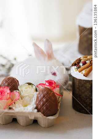White bunny with chocolate eggs and roses in carton, Easter still life, soft bokeh White bunny with chocolate eggs and roses in carton, Easter still life, soft bokeh 136135864