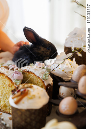 Black baby bunny with sliced Easter cake and festive spring dessert table Black baby bunny with sliced Easter cake and festive spring dessert table 136135867