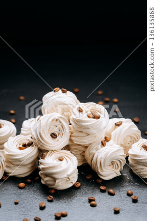 Vanilla zephyr meringue cookies with coffee beans on dark slate background Vanilla zephyr meringue cookies with coffee beans on dark slate background 136135868