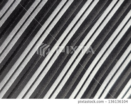 Close-up of the fabric of a men's tie with diagonal black and silver stripes. The accessory is made of microfiber 136136104