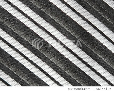 A close-up of the fabric of a men's tie with diagonal black and silver stripes. Accessory is made of microfiber 136136106