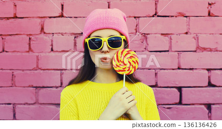 stylish modern young woman with lollipop in colorful clothes 136136426