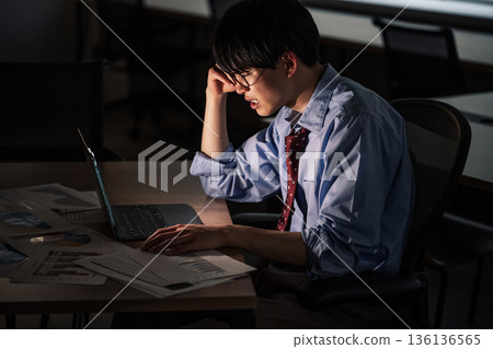 A young businessman who works overtime because he can't finish his work until late at night 136136565