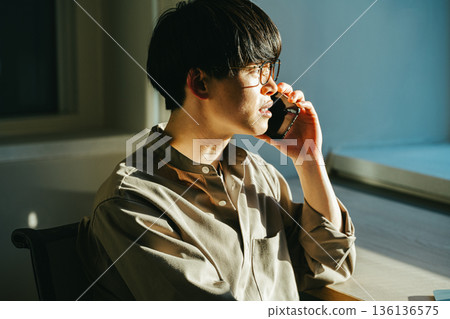 日落時分,一位年輕男子正在用智慧型手機通話。 日落時分,一位年輕男子正在用智慧型手機通話。 136136575
