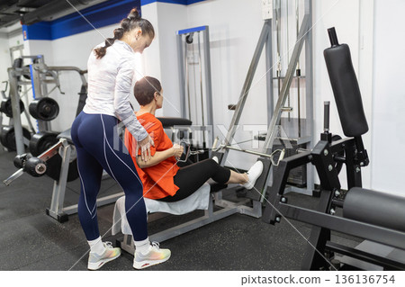 Personal trainer guiding woman during gym workout session Personal trainer guiding woman during gym workout session 136136754