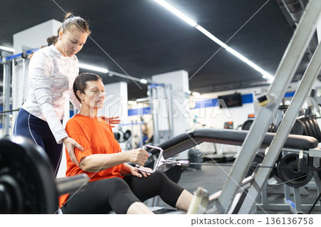 Senior woman exercising with personal trainer assistance Senior woman exercising with personal trainer assistance 136136758
