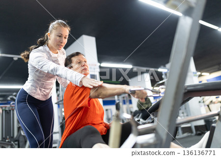 Personal trainer assisting senior woman working out Personal trainer assisting senior woman working out 136136771