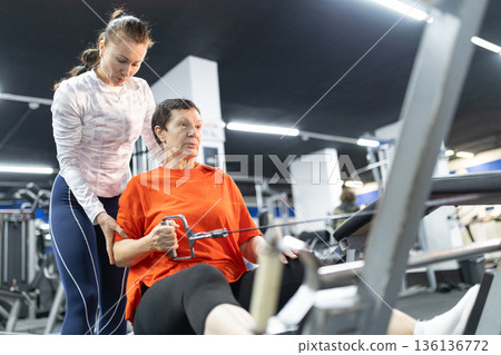 Senior woman training with personal trainer at gym 136136772