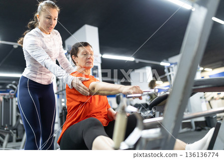Senior woman training with personal coach in modern gym 136136774