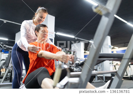 Personal trainer helping senior woman with gym exercise Personal trainer helping senior woman with gym exercise 136136781