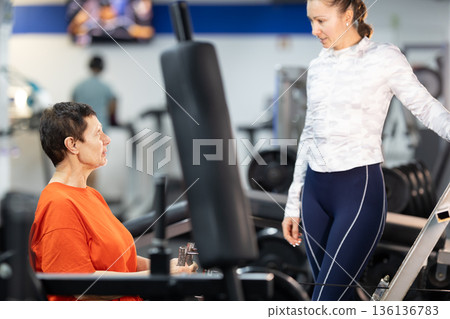 Personal trainer assisting senior woman during gym workout Personal trainer assisting senior woman during gym workout 136136783