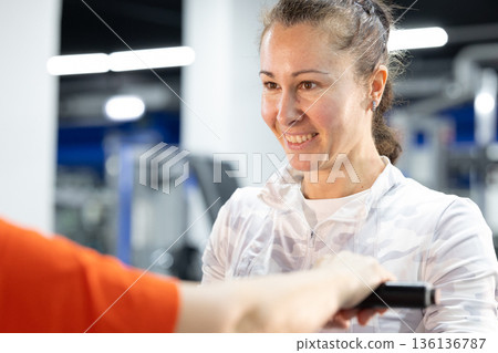 Woman smiling and training with a fitness instructor in gym 136136787