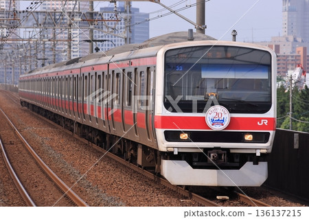 209系列列車行駛在京葉線上，背景為市中心建築。照片拍攝於2010年6月13日。 136137215