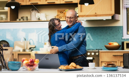 Smiling aged husband and wife sharing a romantic dance in the kitchen, waltzing together on a passionate love song and flirting with each other. Holding hands and slow dancing, swaying. Camera B. Smiling aged husband and wife sharing a romantic dance in the kitchen, waltzing together on a passionate love song and flirting with each other. Holding hands and slow dancing, swaying. Camera B. 136137534