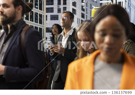 Indian male entrepreneur navigating on his phone through busy city street, showing urban crowd, pedestrians and dynamic activity. Everyday business lifestyle in modern metropolitan environment. Indian male entrepreneur navigating on his phone through busy city street, showing urban crowd, pedestrians and dynamic activity. Everyday business lifestyle in modern metropolitan environment. 136137699
