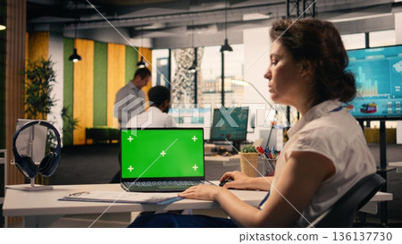 Isolated chroma key laptop in a multinational company office, businesswoman working at desk with KPI and visual data. Employee does organizational planning and performance review. Isolated chroma key laptop in a multinational company office, businesswoman working at desk with KPI and visual data. Employee does organizational planning and performance review. 136137730