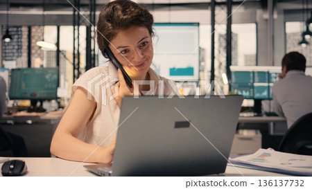 Businesswoman making phone call in modern office reviewing visual data, sharing KPI and monetary data via smartphone line, networking and reporting. Global business and corporate lifestyle. Businesswoman making phone call in modern office reviewing visual data, sharing KPI and monetary data via smartphone line, networking and reporting. Global business and corporate lifestyle. 136137732