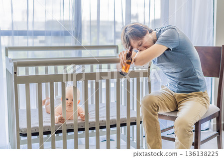 Sad father sitting beside his baby crib holding a bottle of beer at home. Emotional scene highlighting parental burnout and depression. Mental health awareness, fatherhood struggle and hidden emotions 136138225
