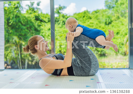 Mother doing fitness exercises while holding her baby at home, combining workout and childcare. Real lifestyle moment showing balance, strength and love. Postpartum fitness, healthy motherhood and Mother doing fitness exercises while holding her baby at home, combining workout and childcare. Real lifestyle moment showing balance, strength and love. Postpartum fitness, healthy motherhood and 136138288