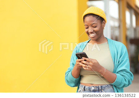 Smiling young woman wearing yellow cap using Smiling young woman wearing yellow cap using 136138522