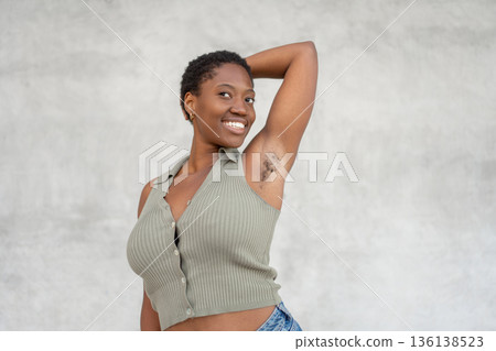 Smiling black woman showing underarm hair against Smiling black woman showing underarm hair against 136138523