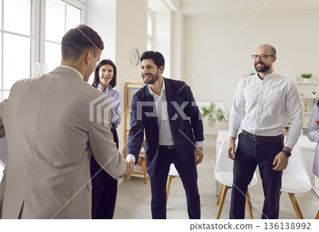 Business people standing in office making deal on meeting. Two cheerful men shaking hands. 136138992