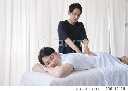 女按摩師正在為男士按摩下背部 136139416