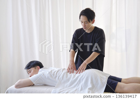 女按摩師正在為男士按摩下背部 136139417
