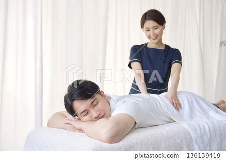 女按摩師正在為男士按摩下背部 136139419