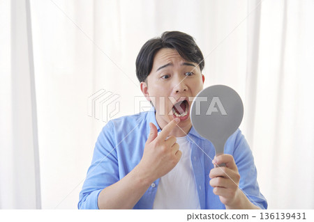 一名 20 多歲的男子因蛀牙而照鏡子 136139431