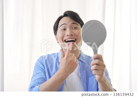 20 多歲的男子照鏡子，進行牙科護理 136139432