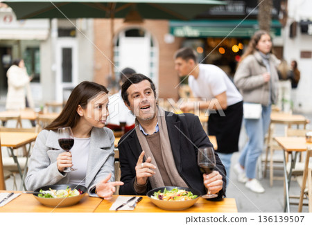 Girl in cafe sits near male companion, has nice conversation and discusses news of day 136139507