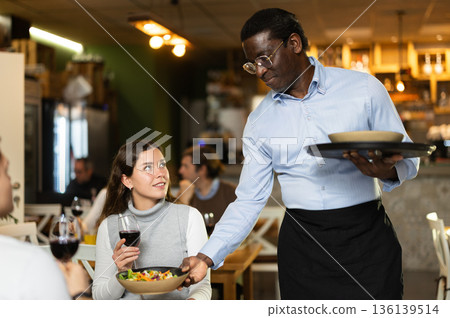 African waiter with tray in hands bringing food 136139514