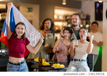 Men and women supporting Czech sports team in pub together. Group of friends raising Czech flag 136139516