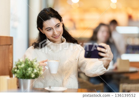 Young woman with phone in cafe Young woman with phone in cafe 136139552