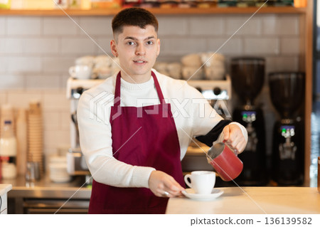 Barista in red apron brewing coffee for client Barista in red apron brewing coffee for client 136139582