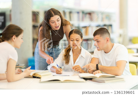 Group of students reading books and taking notes in library Group of students reading books and taking notes in library 136139601