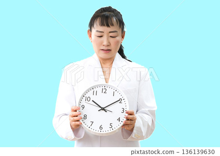 一位身穿白大褂的女士和一座鐘 136139630
