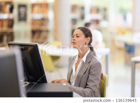 Young female student working on computer in library 136139645