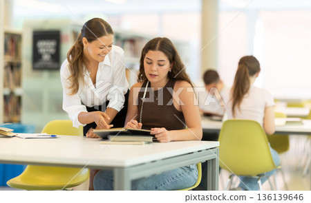 Women students study together in the library Women students study together in the library 136139646