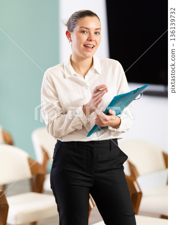 woman secretary with a folder with documents in her hands invites students and office workers woman secretary with a folder with documents in her hands invites students and office workers 136139732