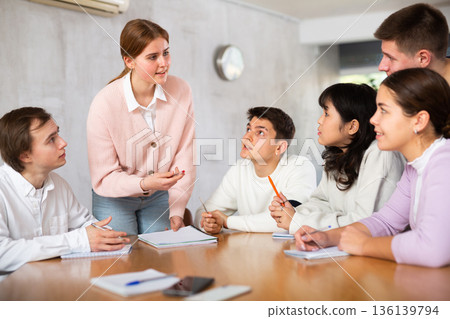 Young female tutor teaching group of students in college Young female tutor teaching group of students in college 136139794