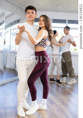 Dance studio - students in casual clothes learn to dance tango Dance studio - students in casual clothes learn to dance tango 136139822